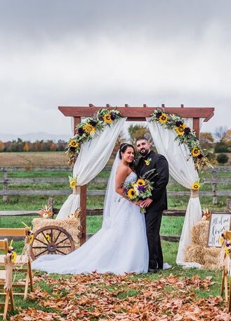 A couple getting married in the fall inside of a field at one of the vermont wedding venues that offers Adirondack views in the background.